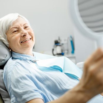 woman admiring her smile after getting dental implants in Oak Cliff 