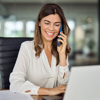 Woman smiling while talking on phone in office