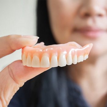 a person holding their dentures in Kessler Park