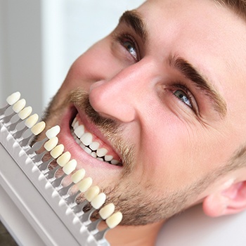 Man's smile compared with tooth color chart