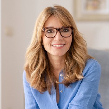 Woman with glasses sitting on couch and smiling