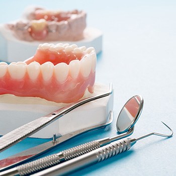 A lower denture sitting next to dental tools