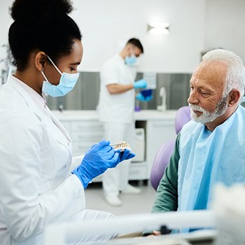A dentist explaining dentures’ oral health benefits to an older man