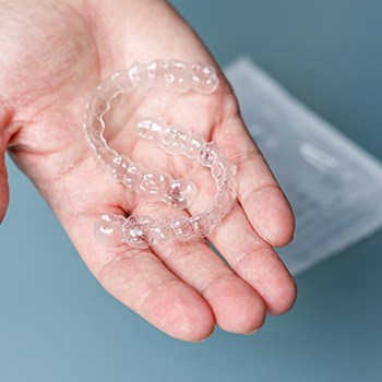 person holding two clear aligners