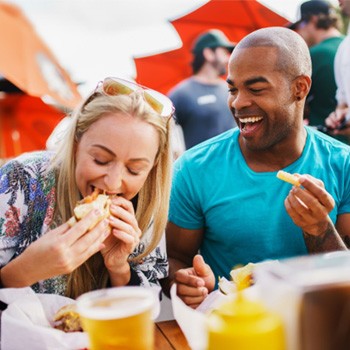 Friends smiling while eating lunch together outside