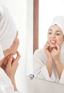 Woman looking at her teeth in bathroom mirror