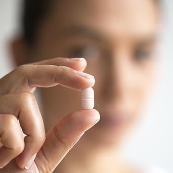 Hand holding a white antibiotic pill