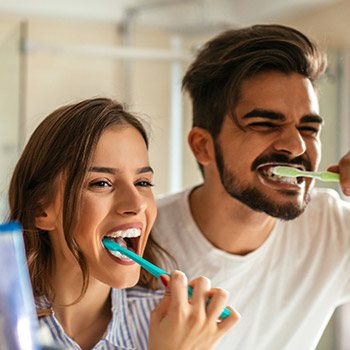 Man and woman brushing teeth together