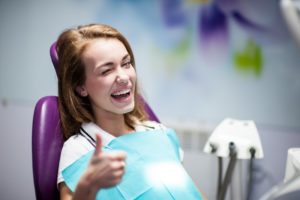 woman smiling thumb up dentist chair