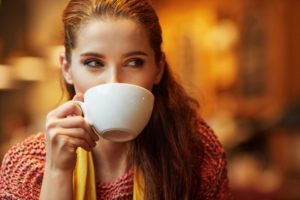 A woman drinking from a mug.