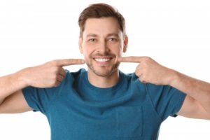 Smiling man pointing at his new porcelain veneers