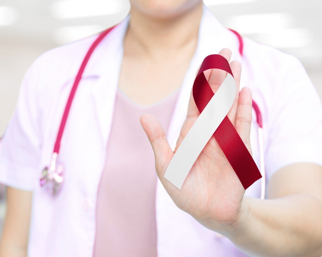 Doctor holding red and white ribbon for oral cancer awareness month