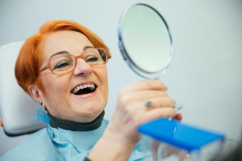 An older woman enjoying the look of her new dentures in a mirror